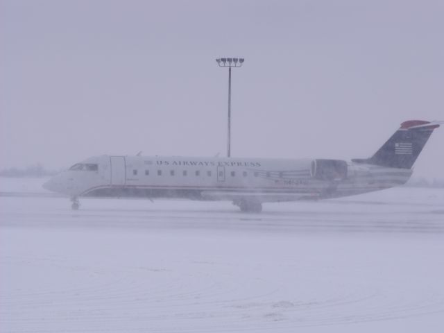 Canadair Regional Jet CRJ-200 (N462AW) - snow blowing towards aircraft as 737 departs.