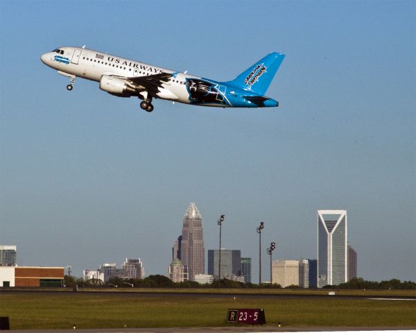 Airbus A319 (N717UW) - The Panthers plane zipping by downtown Charlotte, North Carolina USA. Its a warm 1 October evening with a beautiful blue sky.