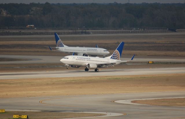 Boeing 737-700 (N16713) - COA 737 landing on 26L, while another COA 737 waits to cross after landing on 26R.