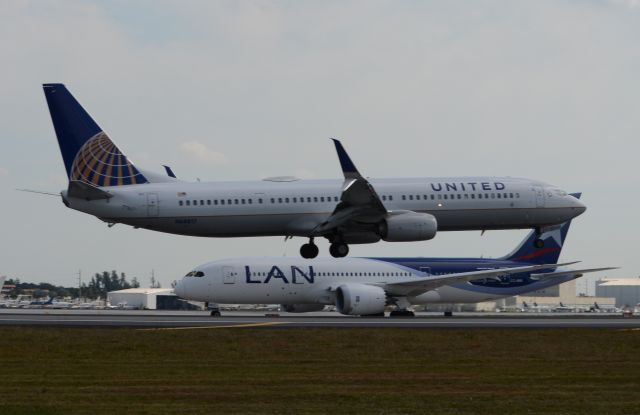 Boeing 737-900 (N68817) - Landing on RWY 12, while LAN 787-8 CC-BBE holds short at RWY 8R